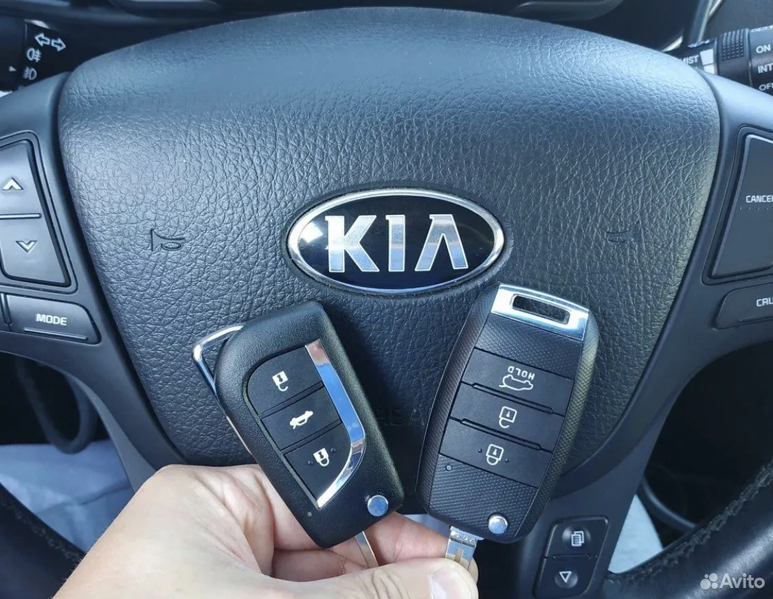 Автоключи Kia на фоне руля автомобиля
